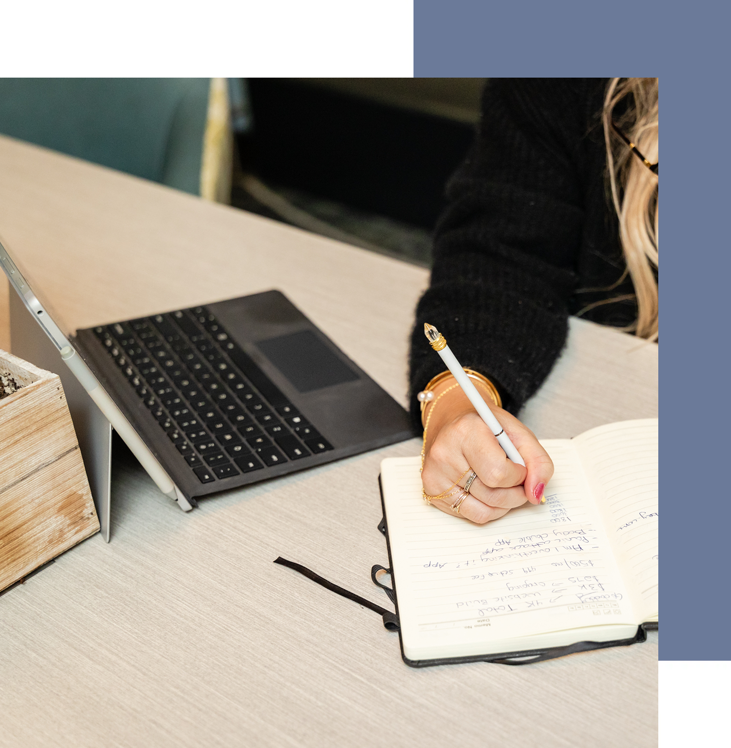 A person writing in a notebook next to a laptop.