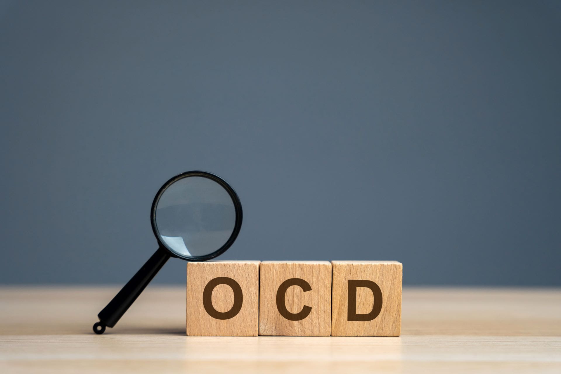 A magnifying glass sitting on top of blocks that spell " ocd ".