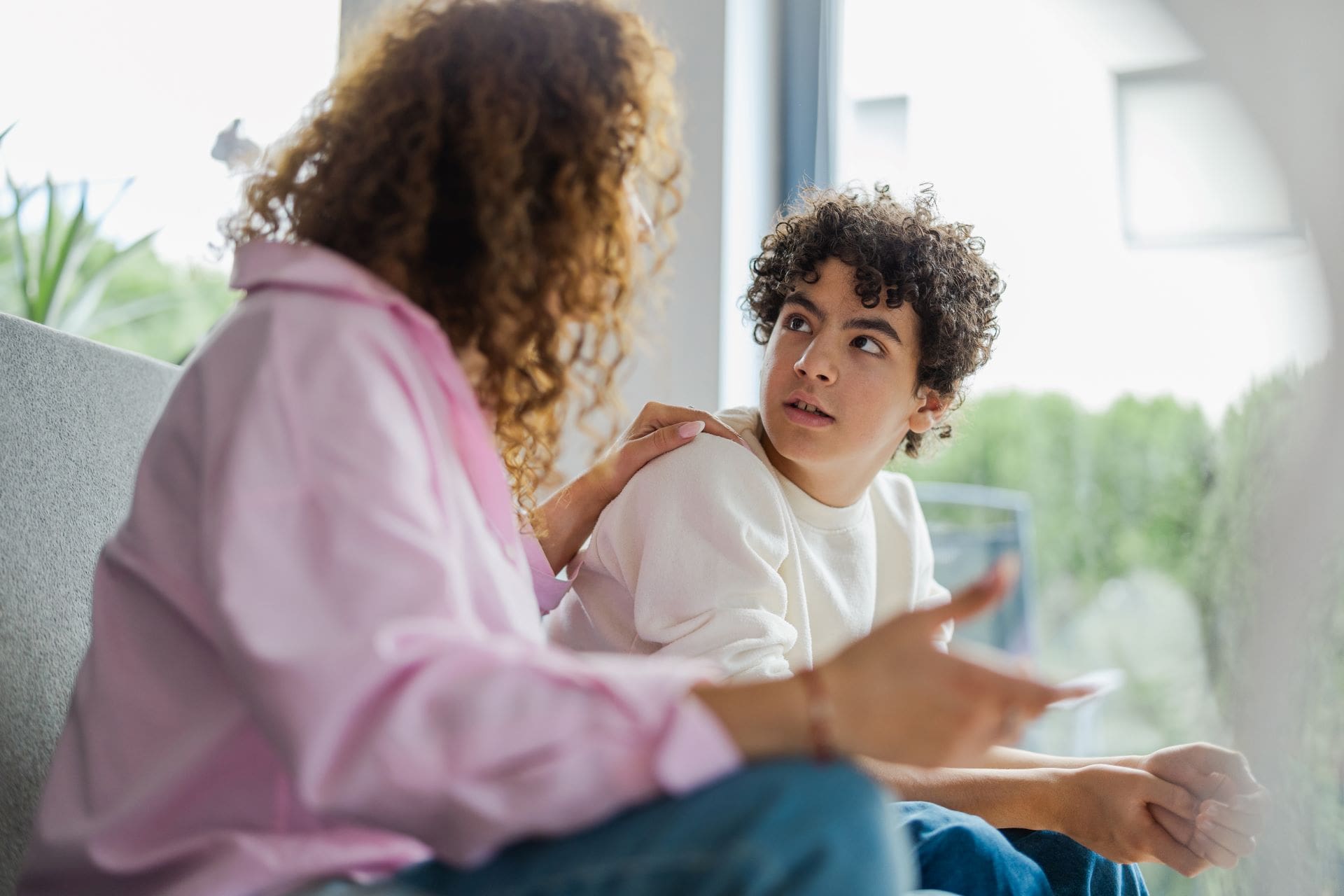 A woman and boy sitting on the couch talking.