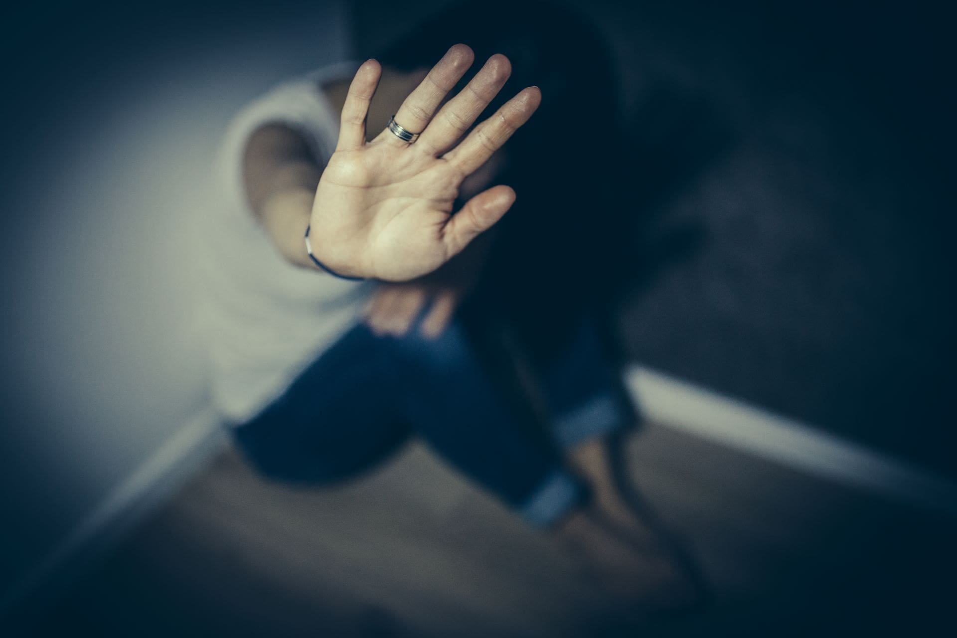 A person sitting on the ground with their hands up.