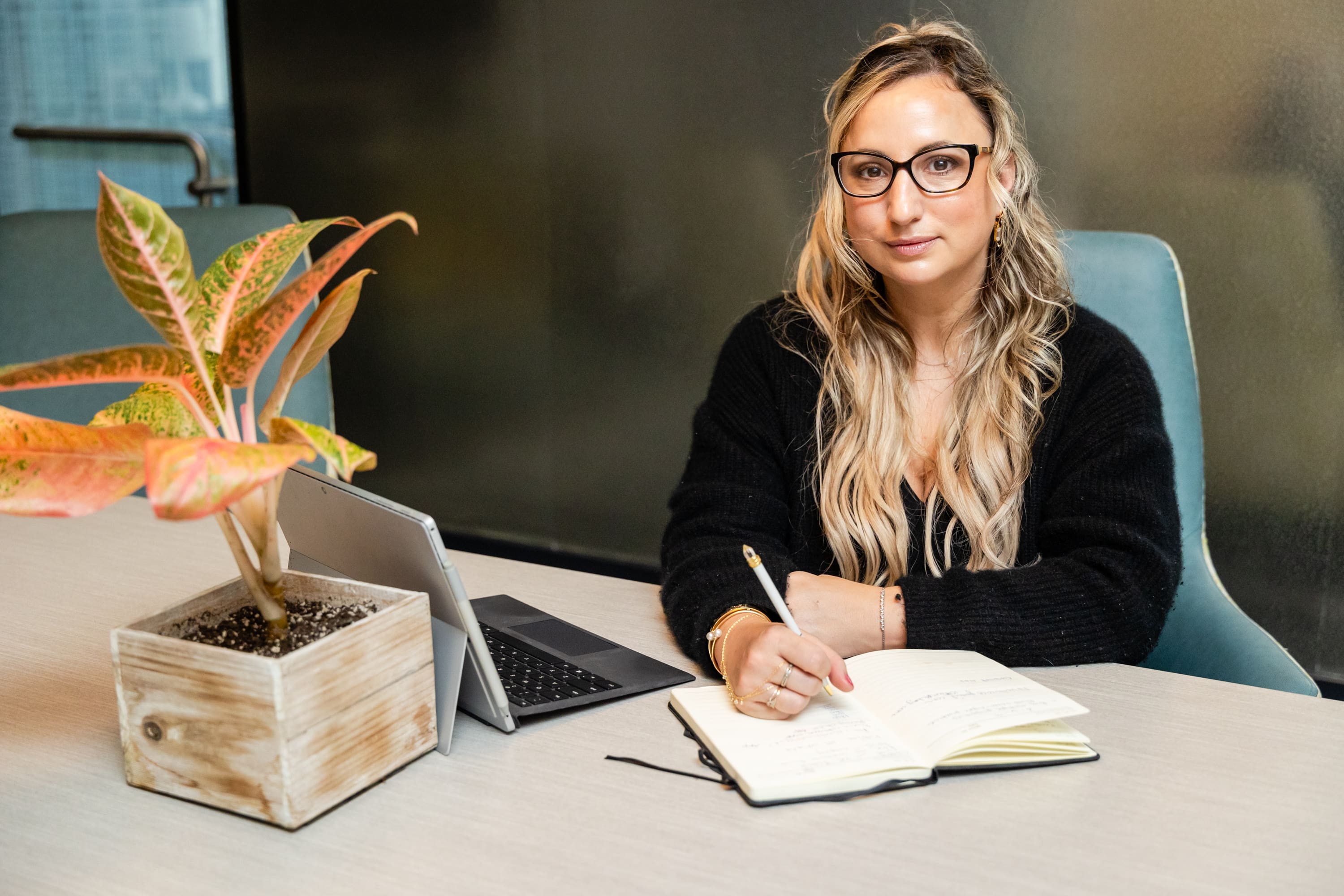 A woman sitting at a table with a laptop and notebook.