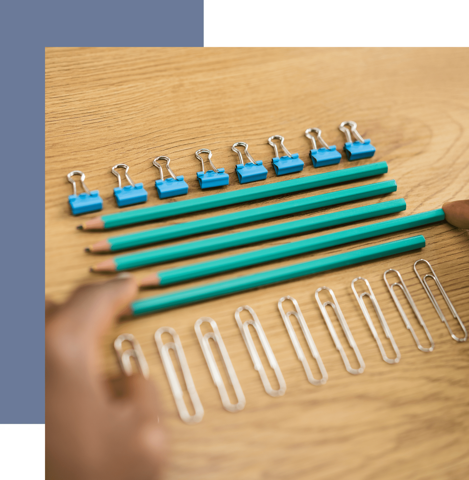 A person is holding some binder clips and pencils