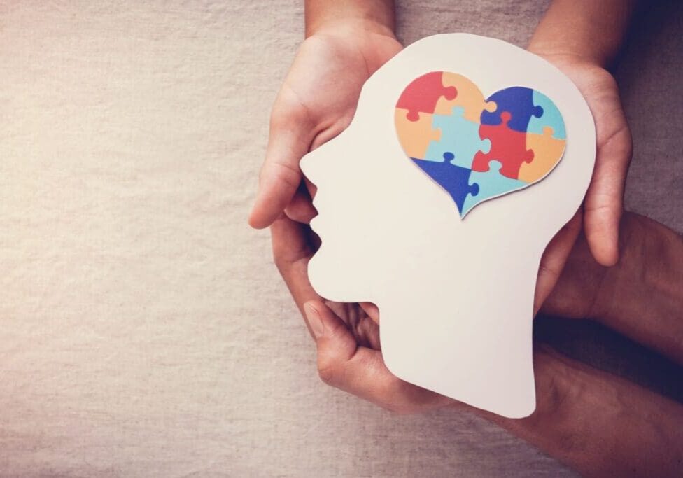 A person holding a puzzle heart in their head.