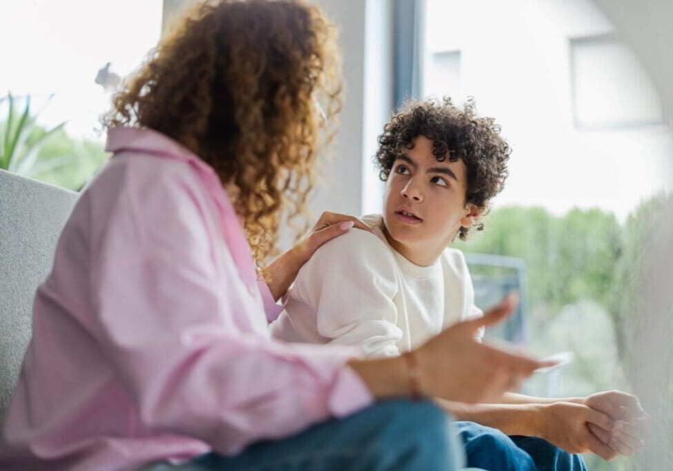 A woman and boy sitting on the couch talking.