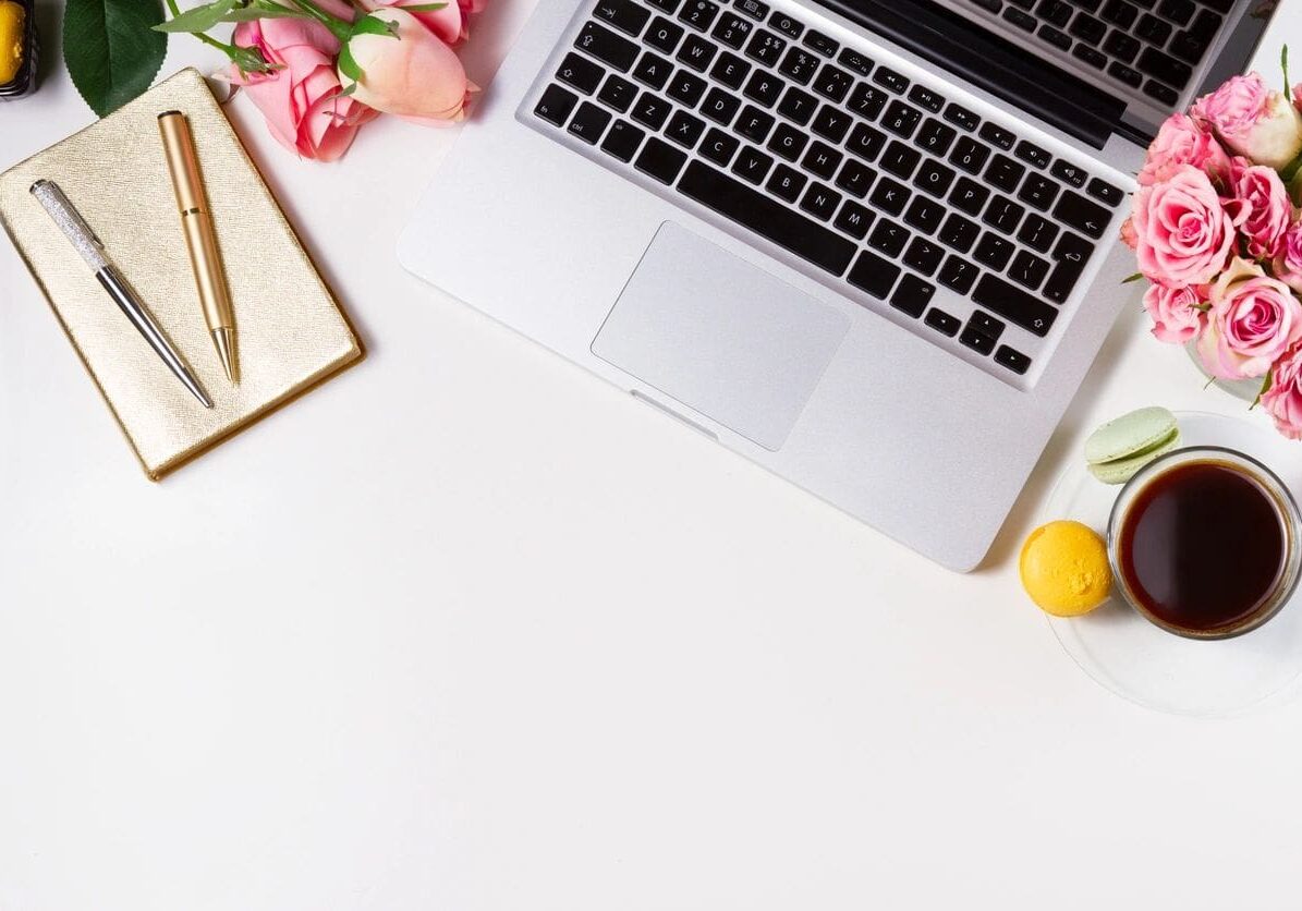 A laptop and some flowers on top of a desk.